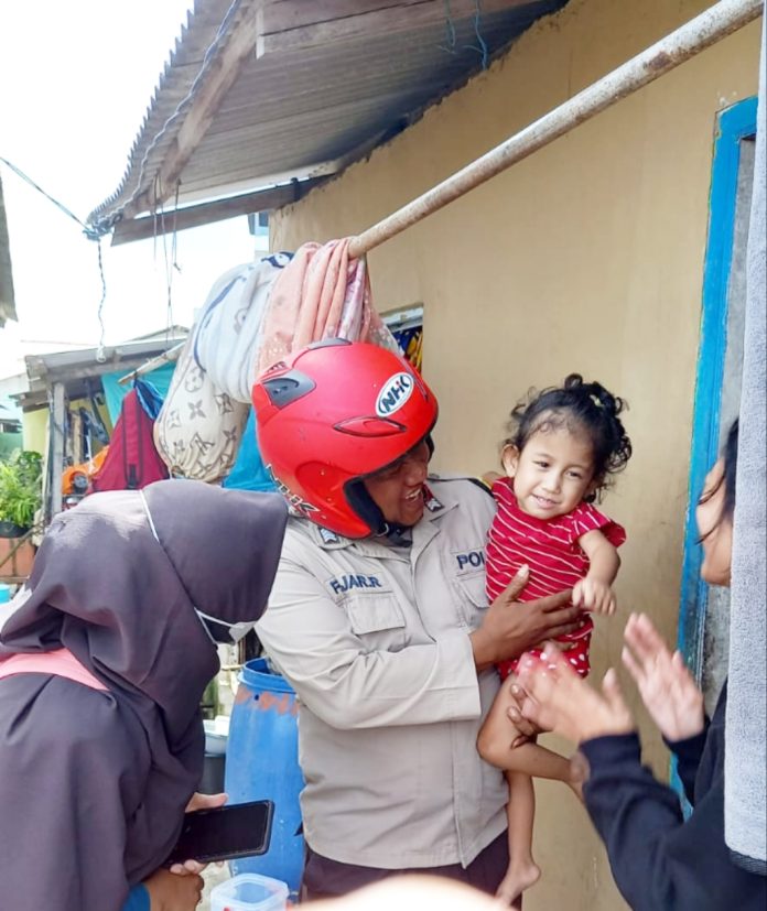 Bhabinkamtibmas Polsek Tanjungpinang Barat Bripka Fajar Ramadhan memberikan makanan tambahan kepada salah satu warga masyarakat Kelurahan Tanjungpinang Barat, Kecamatan Tanjungpinang Barat, Rabu (4/1) F,Polresta Tanjungpinang