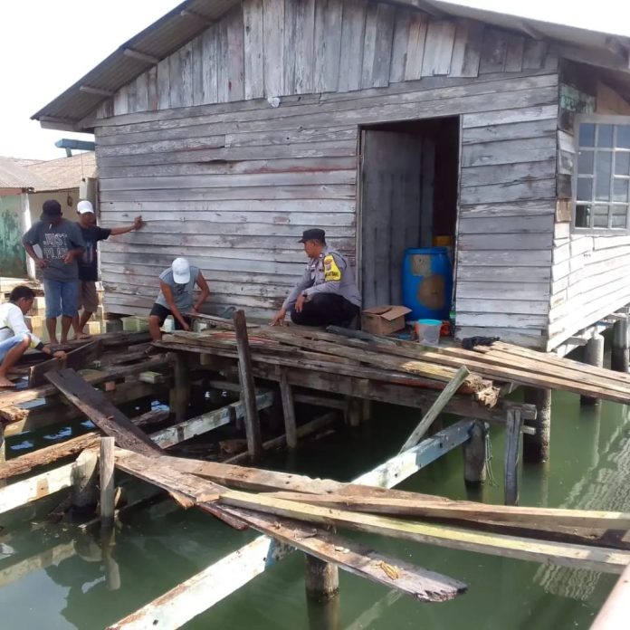 Bhabinkamtibmas Kelurahan Tanjung Unggat Polsek Bukit Bestari Polresta Tanjungpinang, Aiptu Razmudi ikut serta membantu salah satu warganya yang memperbaiki rumah di Rw 06 Kelurahan Tanjung Unggat, Selasa (10/1) F,Polresta Tanjungpinang