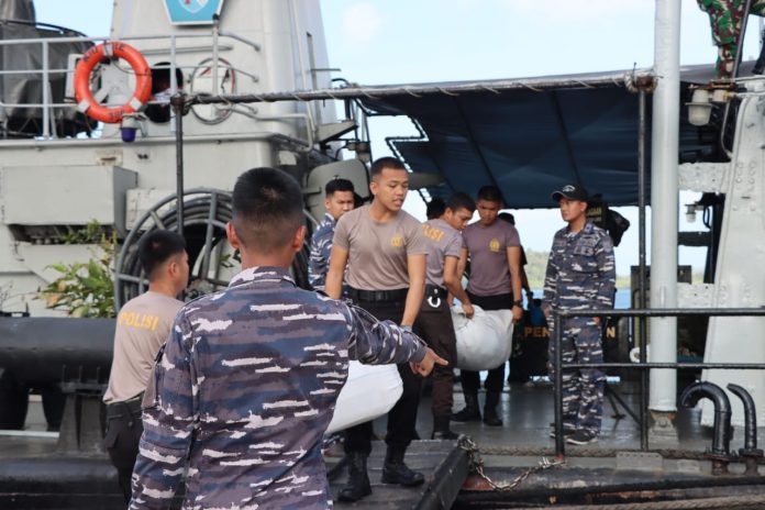 Personil TNI/Polri saat memindahkan bantuan bencana Serasan dari kapal. Bantuan bencana korban longsor di Serasan Kabupaten Natuna dari Kapolri Jendral Polisi. Drs. Listyo Sigit Prabowo dan Ketua Umum Bhayangkari Juliati Sigit Prabowo telah tiba di pelabuhan Serasan, Rabu ( 15/03) F, Polres Natuna