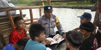 Setelah Dirikan Pondok Baca Presisi, Polsek Bukit Bestari Polresta Tanjungpinang Distribusikan 350 Buku Bacaan Bhabinkamtibmas Kelurahan Tanjung Unggat Aiptu Razmudi saat membaca buku bersama anak-anak Plantar Tanah Merah, Kelurahan Tanjungunggat. Polsek Bukit Bestari Polresta Tanjungpinang distribusikan 350 buku di Pondok Baca Presisi, Kamis, (7/9) f,Polsek Bukit Bestari