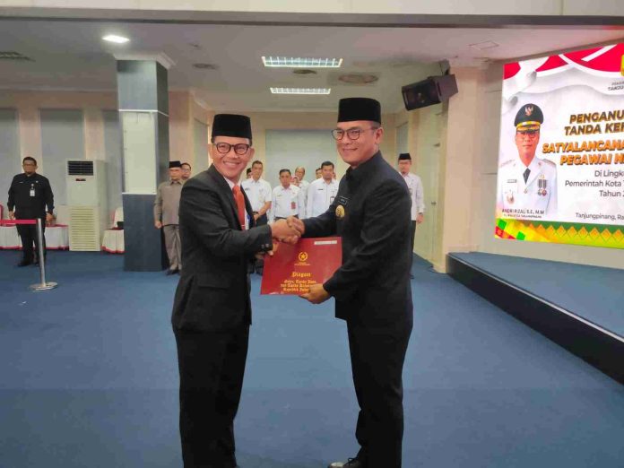 Pj Wali Kota Andri menyerahkan tanda kehormatan Satyalancana Karya Satya tahun 2024 kepada 111 Pegawai Negeri Sipil (PNS) Pemerintah Kota (Pemko) Tanjungpinang di Aula Sultan Sulaiman Badrul Alamsyah Kantor Wali Kota, Senggarang, Rabu (31/7/2024). f,Pemko Tanjungpinang