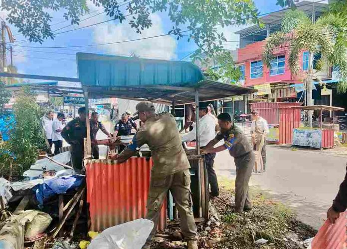 Satuan Polisi Pamong Praja (Satpol PP) Kota Tanjungpinang menertibkan lima unit kios dan lapak pedagang kaki lima (PKL) yang terbengkalai pasca-Ramadan di kawasan Jalan WR Supratman dan Ganet, Kecamatan Tanjungpinang Timur, Selasa (6/5/2025). F, diskominfo Tanjungpinang